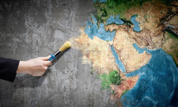 A picture of a hand with a paintbrush bringing color to a map of the world.