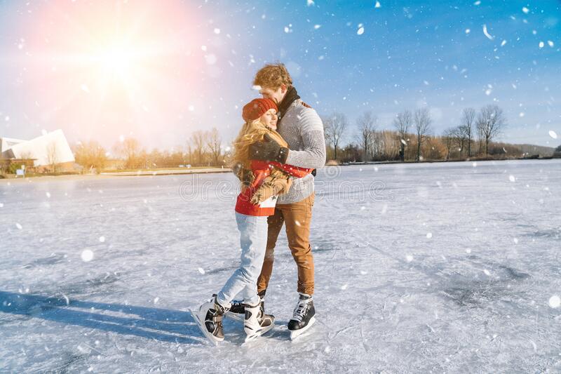Two people ice skating and holding one another in the middle of a snow storm.