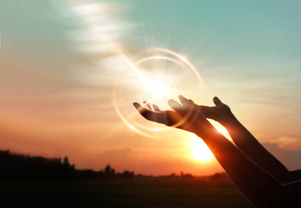 The image is of two hands palm up praying to God in front of a sunrise. The glow from the sun is highlighted in the palms of the hands.