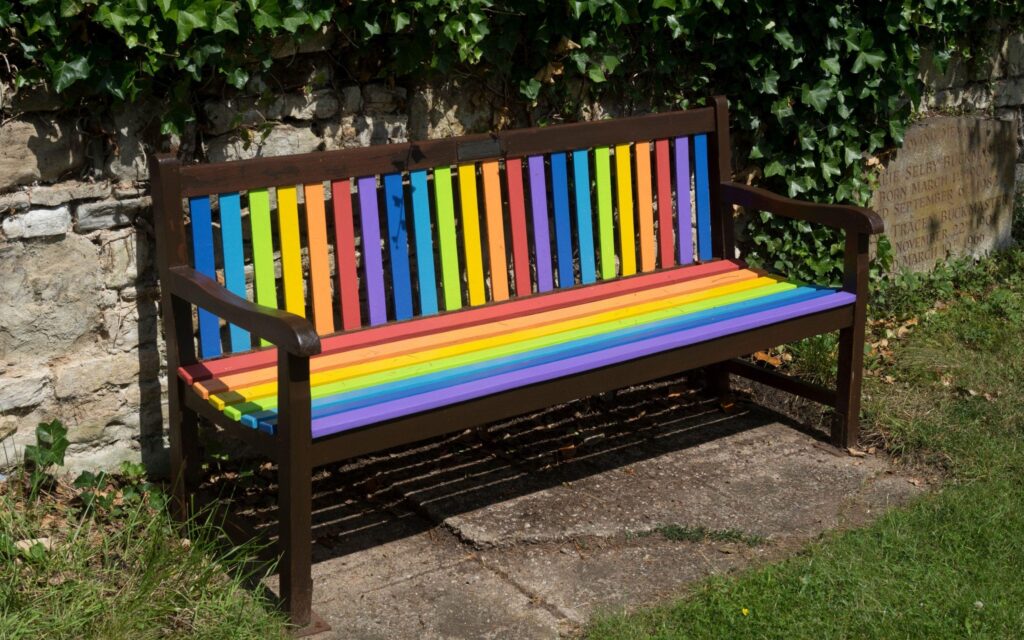 A bench with rainbow slats on the seat and back.
