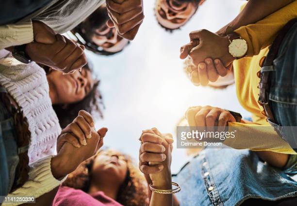 An image of people holding hands in a circle praying.